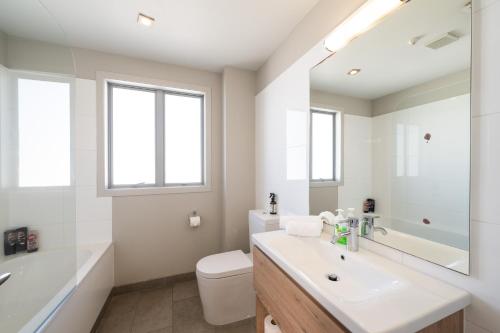 a white bathroom with a sink and a toilet at Beach Front 2 Bedroom Apartment in Paihia