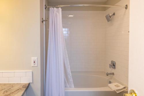 y baño con bañera y cortina de ducha. en Rocky Crest Golf Resort, en MacTier