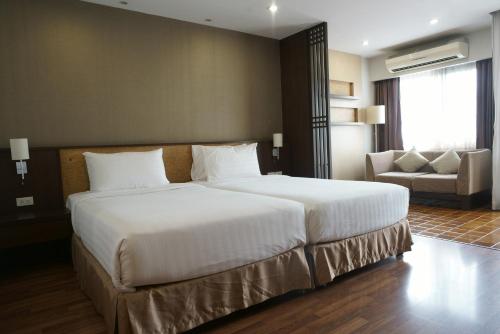 a bedroom with a large white bed and a couch at The Grand Napat in Chiang Mai