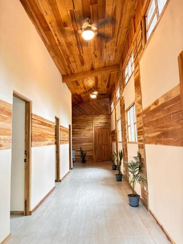 an empty hallway with wooden ceilings and potted plants at Rusteak Living Retreat in natural and peaceful setting in Canafistula in Cañafístula