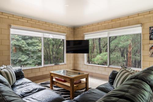 a living room with a couch and two windows at Arcadia Dreaming Chalet Margaret River in Margaret River Town