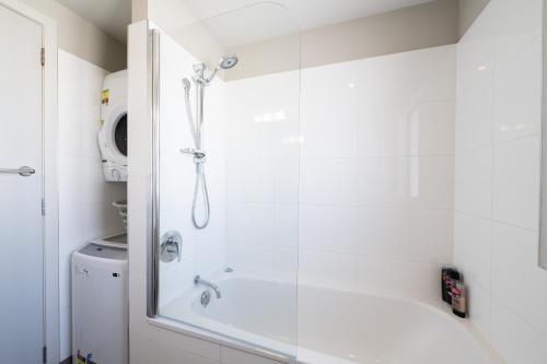 a shower with a glass door next to a washing machine at Beach Front 2 Bedroom Apartment in Paihia
