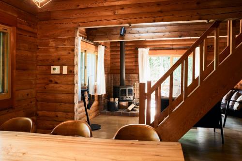 a living room with a staircase in a log cabin at Villa Noël Kitakaruizawa Seiryu Sauna & Open Air Bath in Tsumagoi
