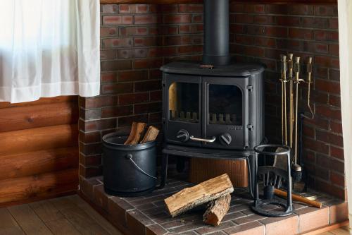 a brick fireplace with a stove and a trash can at Villa Noël Kitakaruizawa Seiryu Sauna & Open Air Bath in Tsumagoi