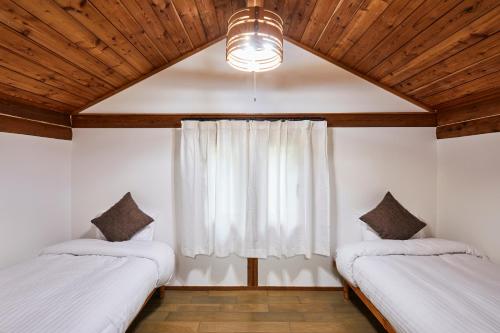 a bedroom with two twin beds and a window at Villa Noël Kitakaruizawa Seiryu Sauna & Open Air Bath in Tsumagoi