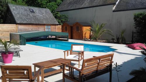 a patio with a table and chairs and a swimming pool at Manoir de la Baronnie in Saint Malo