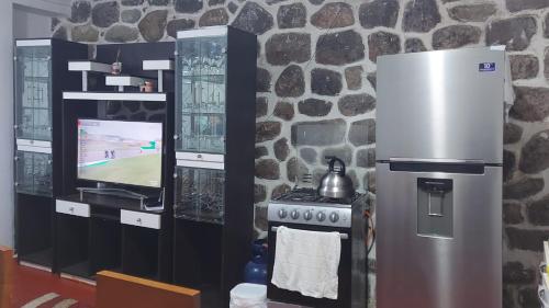 Una cocina con estufa y televisor y una pared de piedra. en Apto Suyana, en Cusco