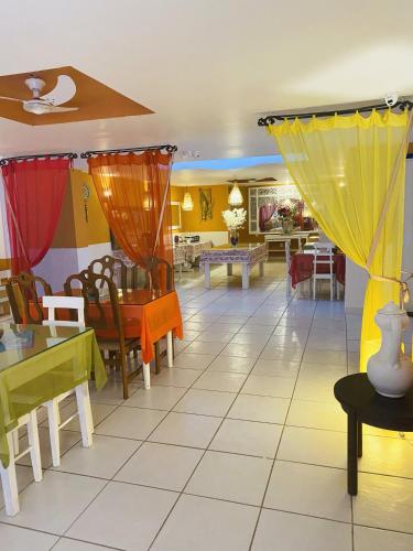 a dining room with tables and chairs and yellow curtains at Villa Baobá Pousada & Spa in Búzios