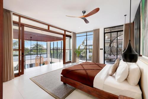 a bedroom with a large bed and large windows at Baliwood Residence Villas by BREIG in Munggu