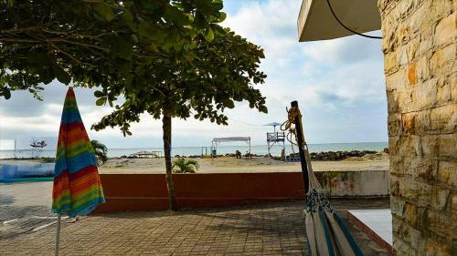 a beach with a rainbow umbrella and a playground at Casa Playa Tonsupa Tu paraíso frente al mar Internet Alta Velocidad Smart TV Netflix in Tonsupa