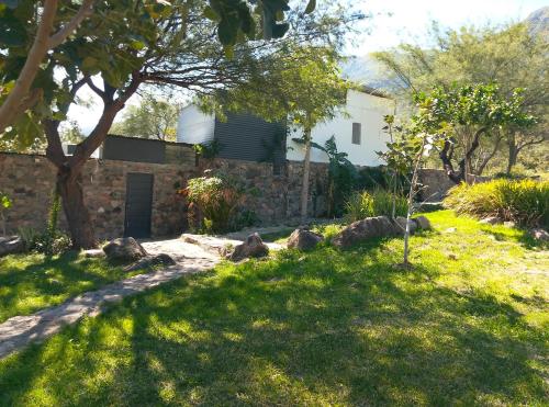 un jardin avec une maison en pierre et un arbre dans l'établissement Finca de montaña agua Gracian, à Pomancillo