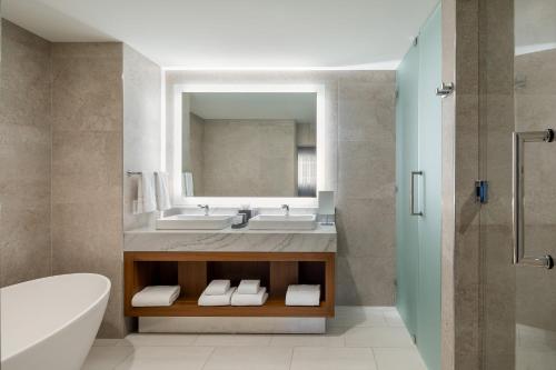 a bathroom with a sink and a tub and a mirror at The Westin Houston Medical Center - Museum District in Houston