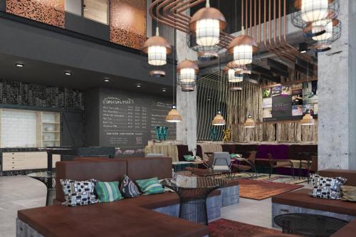 a restaurant with couches and tables and chandeliers at Moxy Poznań Airport in Poznań