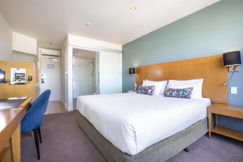 a hotel room with a large bed and a desk at Nightelier Devonport Gateway Hotel in Devonport
