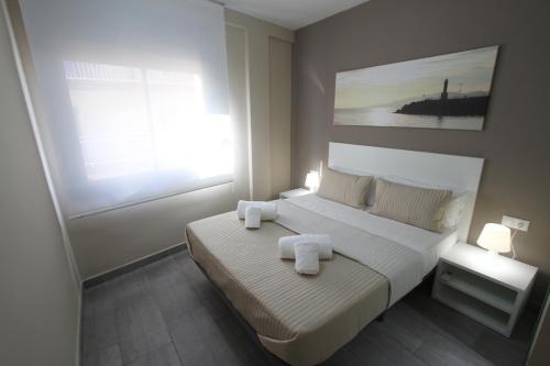 a bedroom with a bed with two towels on it at Apartamentos Cambrils Playa Spa in Cambrils