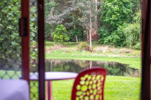 a table and chair with a view of a lake at Nightcap at York on Lilydale in Mount Evelyn