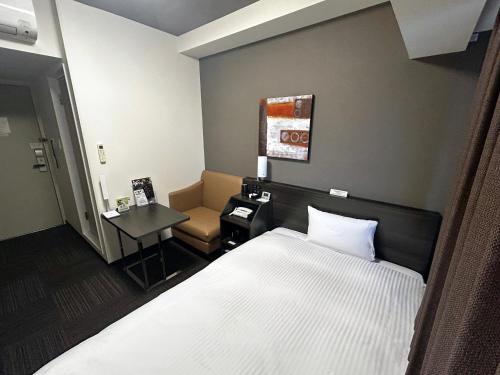 a bedroom with a bed and a table and a chair at Hotel Route Inn Toyama Inter in Toyama