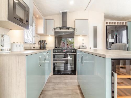 a kitchen with blue cabinets and a stove at Osprey 52 in Saxmundham