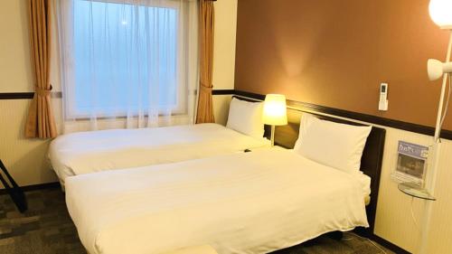 a hotel room with two beds and a window at Toyoko Inn Osaka Abeno Tennoji in Osaka