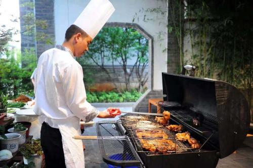 a man is cooking food on a grill at No.3 Garden Hotel in Pi-chi Kuan