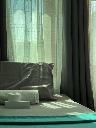 a bed with a pillow and a window with curtains at L Cafe Restobar & Lyn's Guest House in San Juan