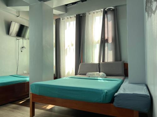 a bedroom with a bed with blue sheets and a window at L Cafe Restobar & Lyn's Guest House in San Juan