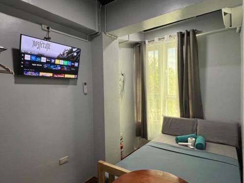 a bedroom with a bed and a tv on the wall at L Cafe Restobar & Lyn's Guest House in San Juan