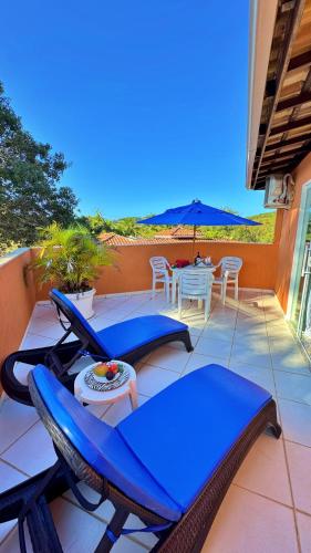 a patio with chairs and a table and an umbrella at Villa Baobá Pousada & Spa in Búzios