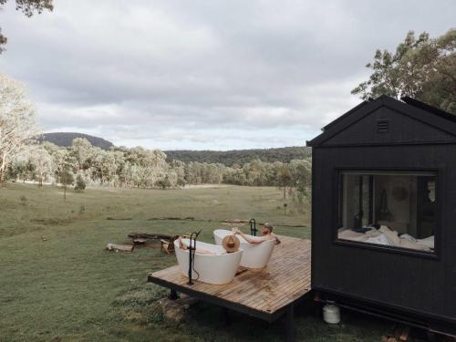 a black tiny house sitting on top of a wooden table at Tiny Maggie in Rylstone