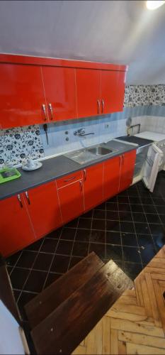a kitchen with red cabinets and a sink at Vuk apartman in Petrovaradin