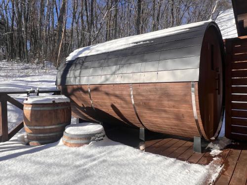 a wooden boat sitting next to two barrels in the snow at Villa Noël Kitakaruizawa Seiryu Sauna & Open Air Bath in Tsumagoi