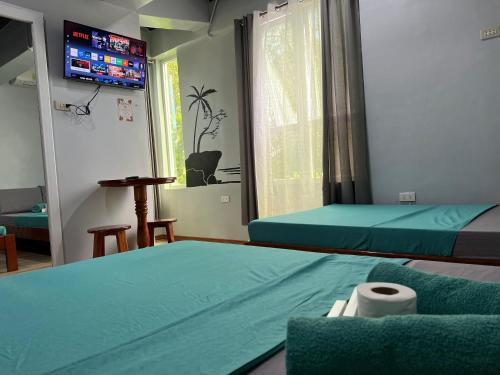 a room with two beds and a tv on the wall at L Cafe Restobar & Lyn's Guest House in San Juan