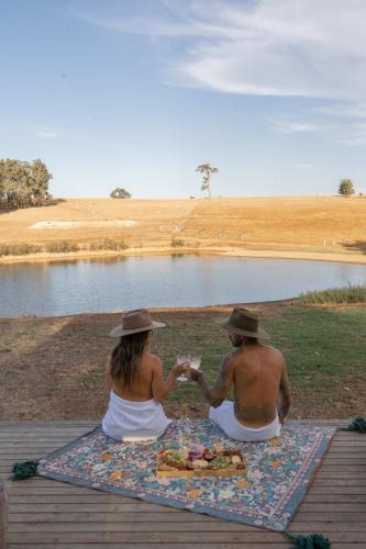 two people sitting on a picnic blanket next to a lake at Tiny Matilda in Bridgetown