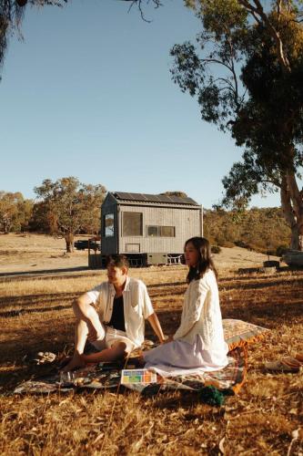a man and woman sitting on a blanket in the grass at Tiny Rosie in Mount Crawford