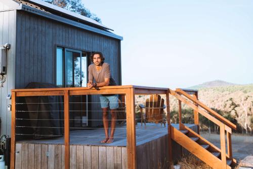 a man standing on the deck of a tiny house at Tiny Rosie in Mount Crawford