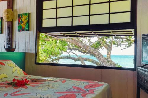 a bedroom with a window looking out at the ocean at TAHITI Tamanu House - Séjour Bord de mer, Plage privée, TV, Wifi, Hôte Polynésienne in Papehee