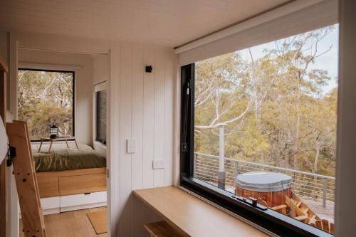 a room with a large window with a bed and a view at Tiny Wombat and Wallaby in Dural