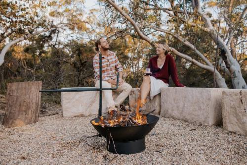 a man and a woman sitting next to a fire at Tiny Wombat and Wallaby in Dural