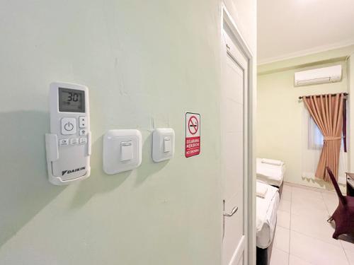 Una habitación de hospital con un reloj electrónico en la pared. en Hotel Permai Syariah RedPartner Sananwetan Blitar, en Karangtengah