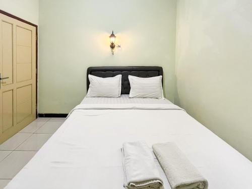 Una cama con sábanas blancas y almohadas en una habitación. en Hotel Permai Syariah RedPartner Sananwetan Blitar, en Karangtengah