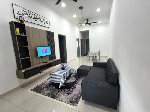 a living room with a black couch and a tv at Little LN Homestay KLIA in Banting