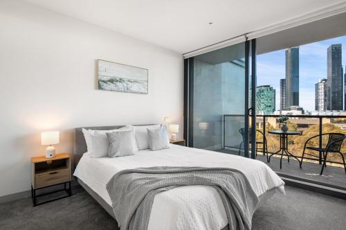 a bedroom with a bed and a large window at Modern 2B2B Apt near Crown with Parking and City Views in Melbourne