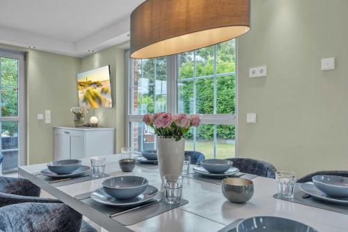 a dining room table with a vase of flowers on it at Haus-Alster-2 in Westerland (Sylt)