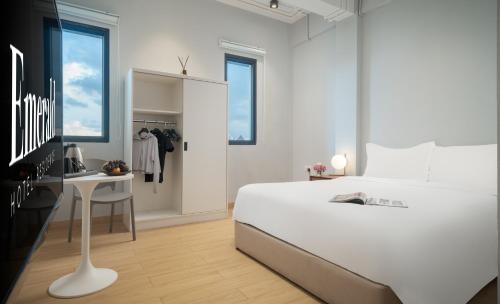 a white bedroom with a large white bed and a desk at Emerald Hotel Residence in Phnom Penh