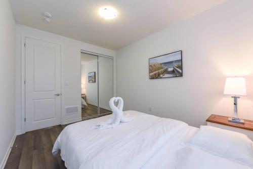 a white bedroom with a white towel animal on a bed at Spacious 4br25ba Retreat W King Beds, Desk, Dt in Milton