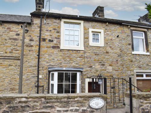 an old stone house with a clock on the front of it at Hallams Yard in Skipton