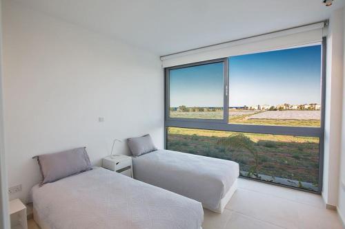 ein Schlafzimmer mit zwei Betten und einem großen Fenster in der Unterkunft Villa Limni Enas - Luxury And Contemporary 3 Bedroom Kapparis Villa With Sea View in Paralimni