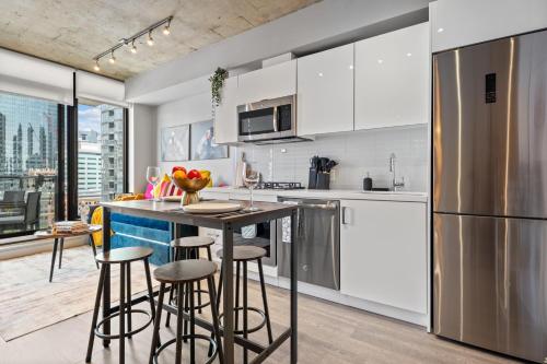a kitchen with white cabinets and a counter with bar stools at Vibrant PopArt downtown suite, comfy and stylish! in Calgary