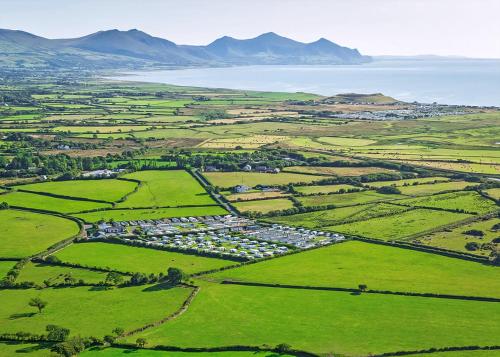 an aerial view of a town with green fields and the ocean at White Tower Holiday Park in Llandwrog