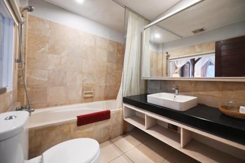 a bathroom with a sink and a toilet and a tub at Puri Dewa Bharata Hotel & Villas in Legian